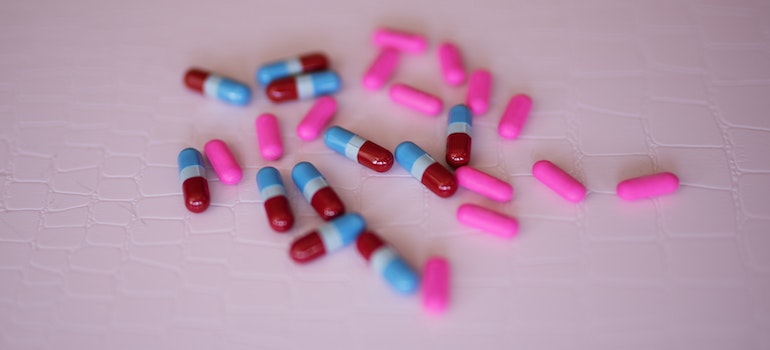 Colorful pills on a pink surface.