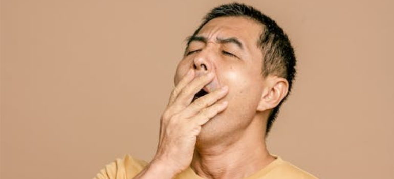 A man in a yellow shirt yawning.