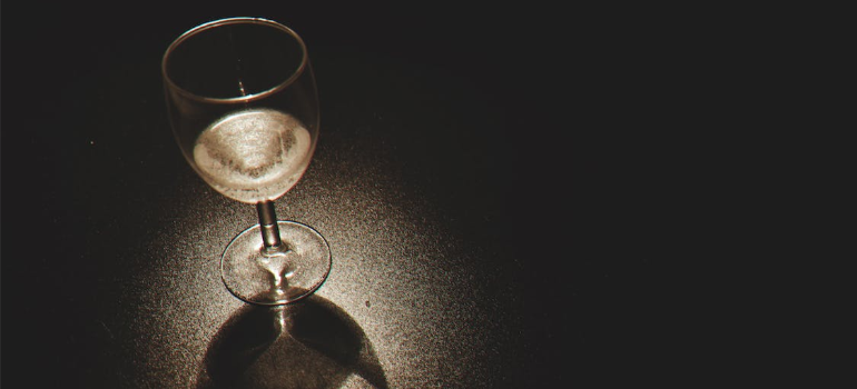 A glass of wine on a black surface, symbolizing how to recognize an alcohol addiction problem.