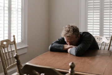 A depressed man lying on a wooden table.