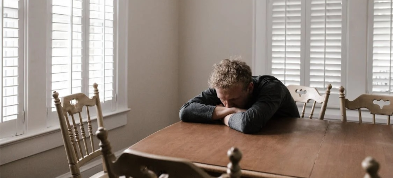 A depressed man lying on a wooden table.