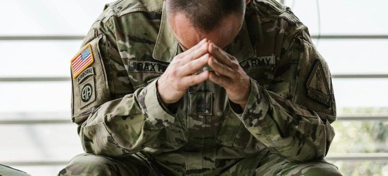 A struggling man in military uniform during a psychotherapy session, representing common addiction relapse triggers.