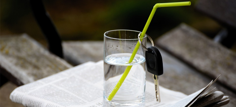 A glass of water with a car key passed through its straw representing alcohol addiction signs