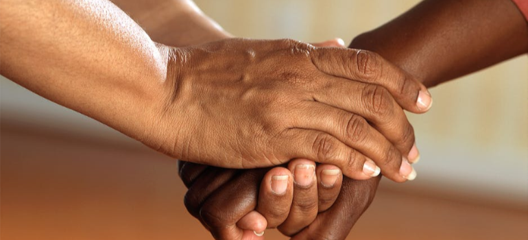 A close-up of a person holding another’s hand, illustrating the benefits of group therapy for addiction Texas.