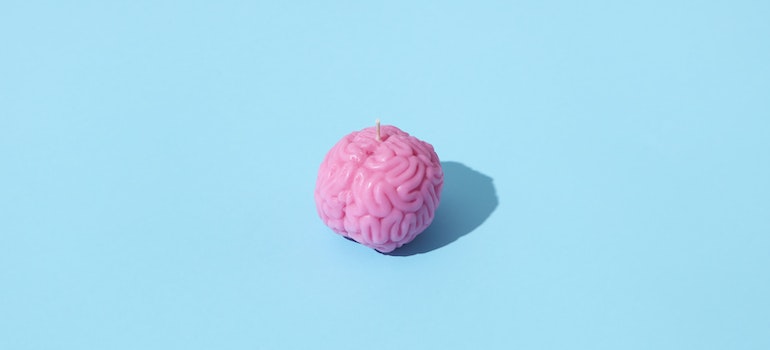 A pink candle in the shape of a brain on a blue surface representing the effects of Xanax on brain and the relationship between Xanax abuse and increased anxiety