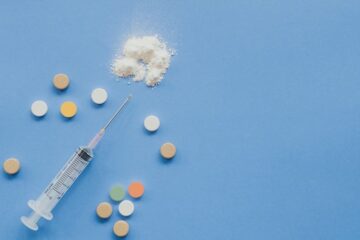 A syringe and drugs on a blue surface