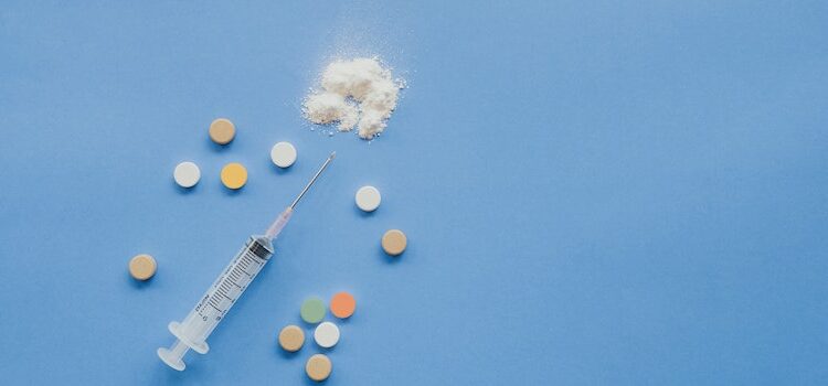 A syringe and drugs on a blue surface