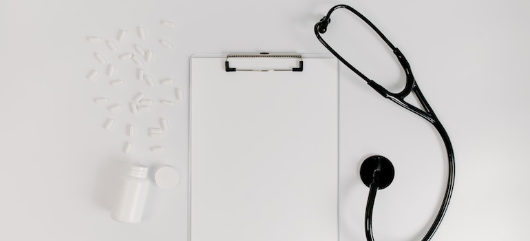 Spilled white pills next to a stethoscope and a blank doctor's notepad representing the relationship between Xanax abuse and increased anxiety