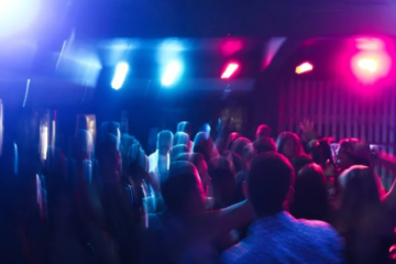 A blurred photo of young people dancing in a night club, illustrating the dangers of alcohol abuse among young adults in San Antonio.