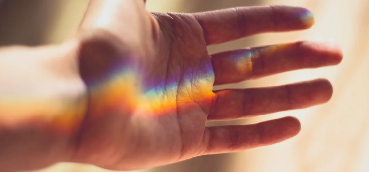 a rainbow reflection on a palm of a and representing mindfulness