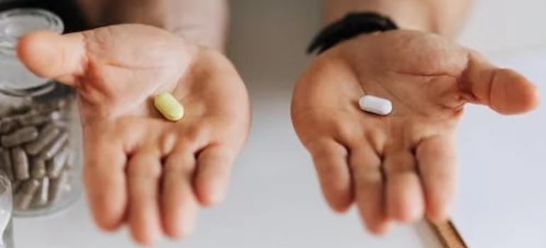 A close-up of a medical professional presenting two pills, illustrating how mental health and substance abuse require simultaneous care.
