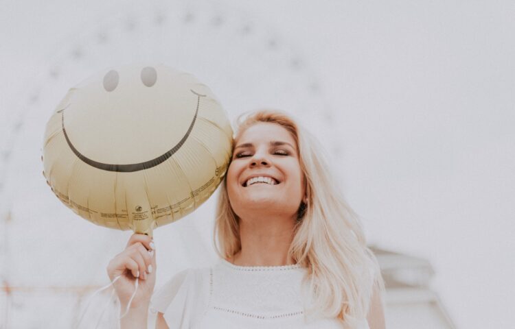 a woman holding a smiley face balloon representing sobriety tracker benefits
