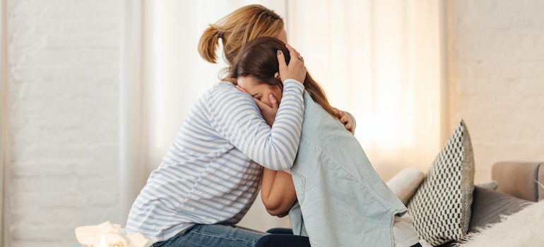 a woman crying embraced by family member representing family involvement in dual diagnosis treatment