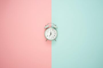 a clock on a pink-blue background representing Time Management in Addiction Recovery