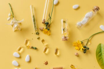 Capsules, vials, and flowers on a yellow background