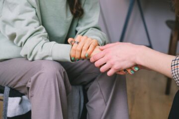 Close-up of two people holding hands in support during the alcohol or drug abuse intervention in San Antonio