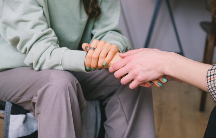 Close-up of two people holding hands in support during the alcohol or drug abuse intervention in San Antonio