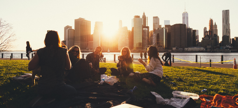 A group of people sitting on the ground as the sun goes down.