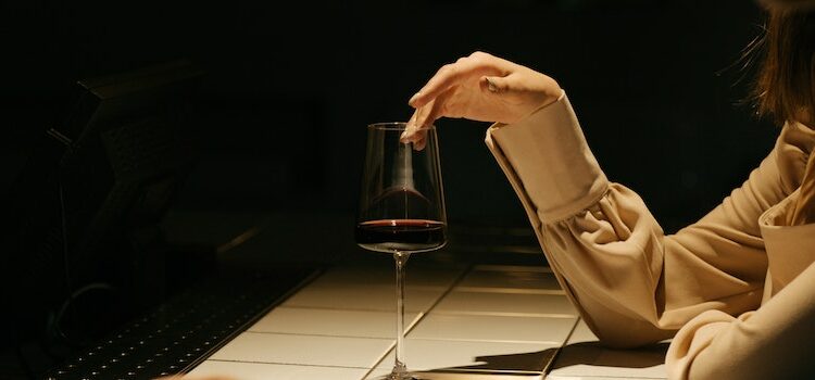close-up of a woman touch a glass of wine representing wine mom culture